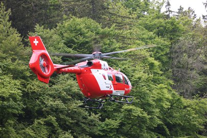 Ein Rettungshelikopter in der Luft vor einem Wald