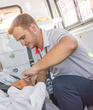 Ein Rega-Pflegefachmann sichert einen Patienten auf der Trage in einem Ambulanzfahrzeug, bevor er zum Rega-Jet gebracht wird.
