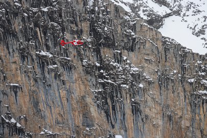 Drei Personen hängen unterhalb des Helikopters am Seil der Rettungswinde