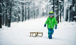 Kind mit Schlitten im Schnee