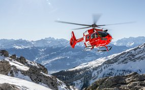 Rega-Helikopter fliegt über Schweizer Schneeberge