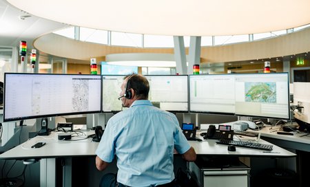 Zum Downloadformular für das Bild Mitarbeiter koordiniert Einsätze an mehreren Bildschirmen in der Einsatzzentrale.