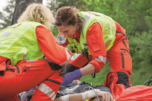 Rega-Rettungssanitäterin Jacqueline Zbaeren leistet zusammen mit einer Kollegin medizinische Hilfe bei einem Einsatz im Gelände.