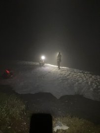 Bergretter auf dem Schnee im Nebel bei Dunkelheit