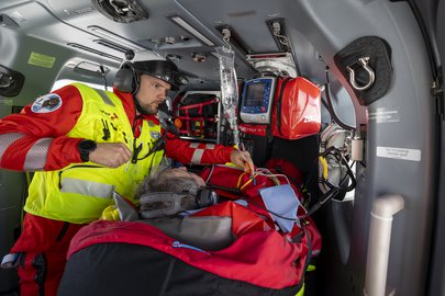 A Rega emergency doctor monitoring a patient inside the medically equipped cabin of a rescue helicopter.