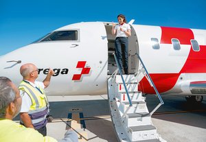  Daniela Bergamin, pilota di jet, sulla scaletta di un jet Rega, saluta qualcuno con il pollice in su. In primo piano sono visibili gli operatori a terra.