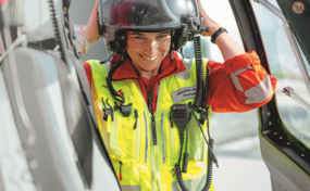 Gros plan de l'ambulancière Rega souriante Jacqueline Zbaeren, mettant son casque de vol.