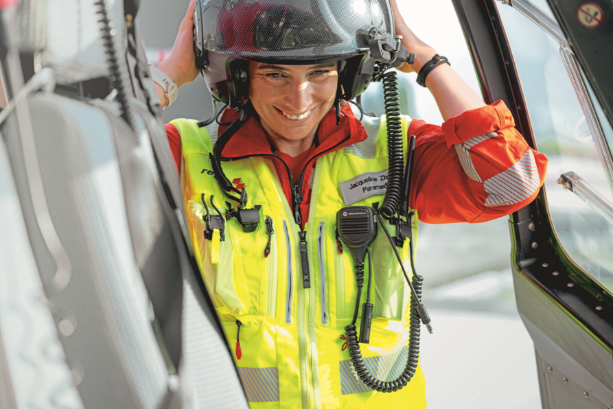 Nahaufnahme der lächelnden Rega-Rettungssanitäterin Jacqueline Zbaeren, die ihren Flughelm aufsetzt.