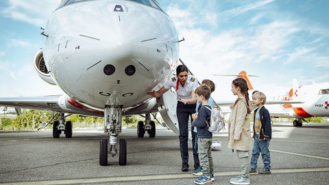 Eine Rega-Pilotin zeigt einer Gruppe von Kindern die Frontpartie eines Ambulanzjets.
