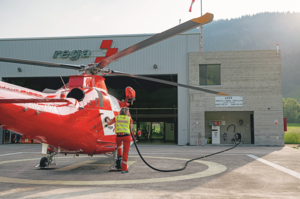 Rega-Crew-Mitglied Jacqueline Zbaeren betankt einen Rettungshelikopter vor dem Hangar der Basis.