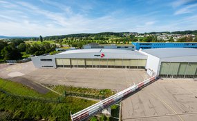 Vue extérieure du Centre Rega à l'aéroport de Zurich, avec les portes du hangar et la place d'atterrissage.