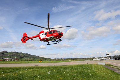 Rega-Helikopter im Landeanflug über einer Wiese