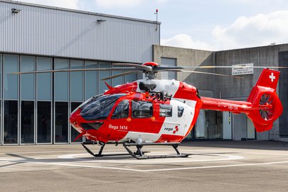 Ein Rega-Rettungshelikopter mit der Kennung HB-TIK vor einem Gebäude.