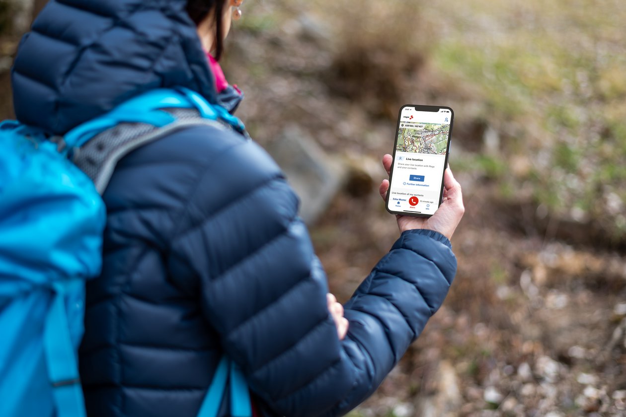 Hiker holding a mobile phone with the Rega app open.